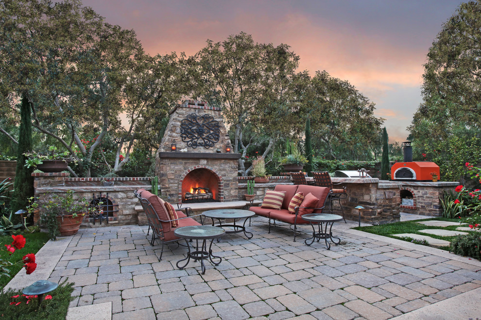 Patio - mid-sized mediterranean side yard stone patio idea in Orange County with a fire pit