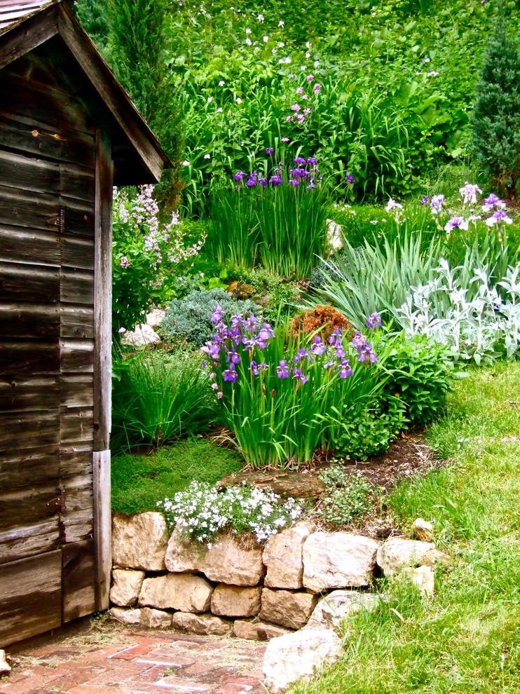 На фото: участок и сад на заднем дворе в классическом стиле с подпорной стенкой с