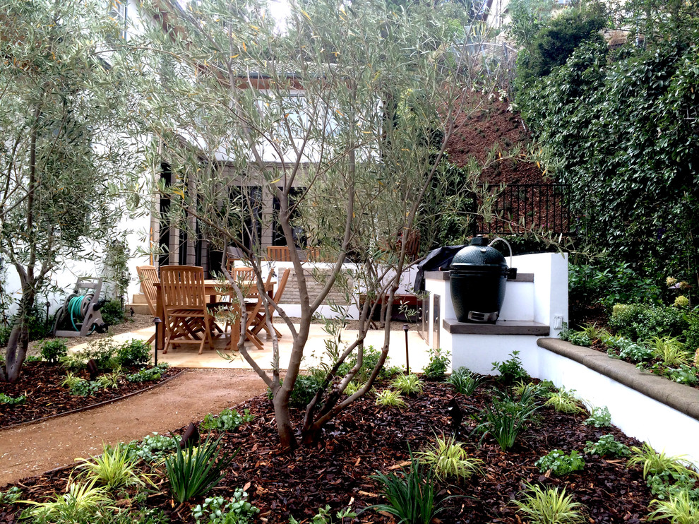 Esempio di un giardino mediterraneo esposto a mezz'ombra di medie dimensioni e dietro casa in primavera con pacciame e un ingresso o sentiero