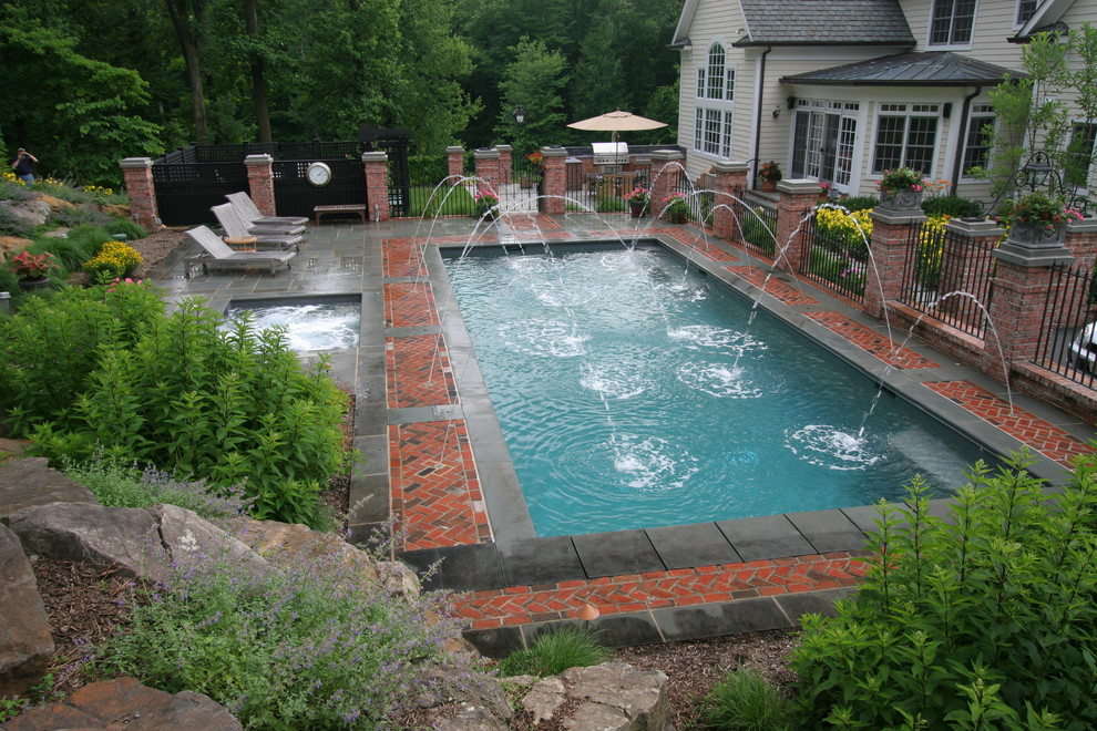 This is an example of an expansive modern back full sun garden for summer in Philadelphia with a water feature and brick paving.