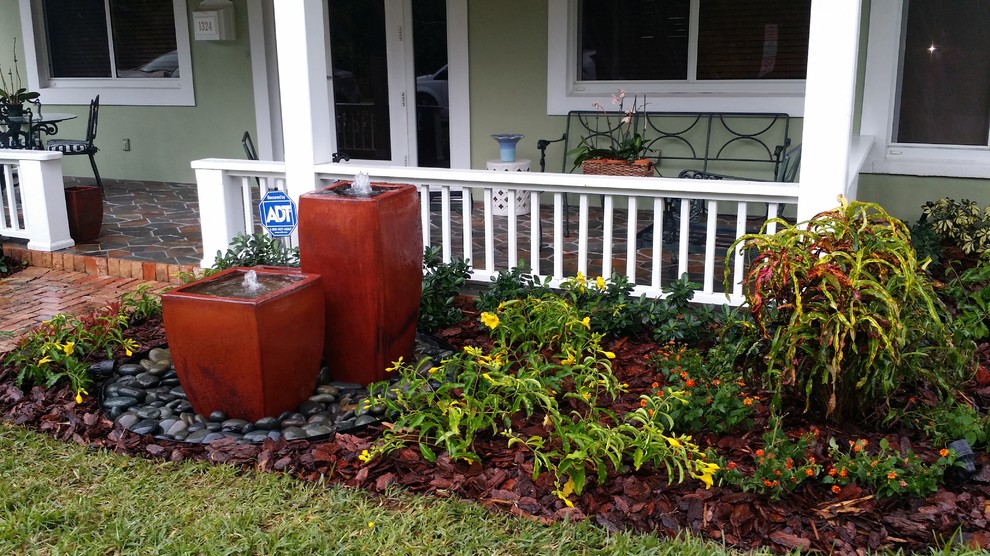 Photo of a mid-sized tropical full sun front yard brick landscaping in Miami.