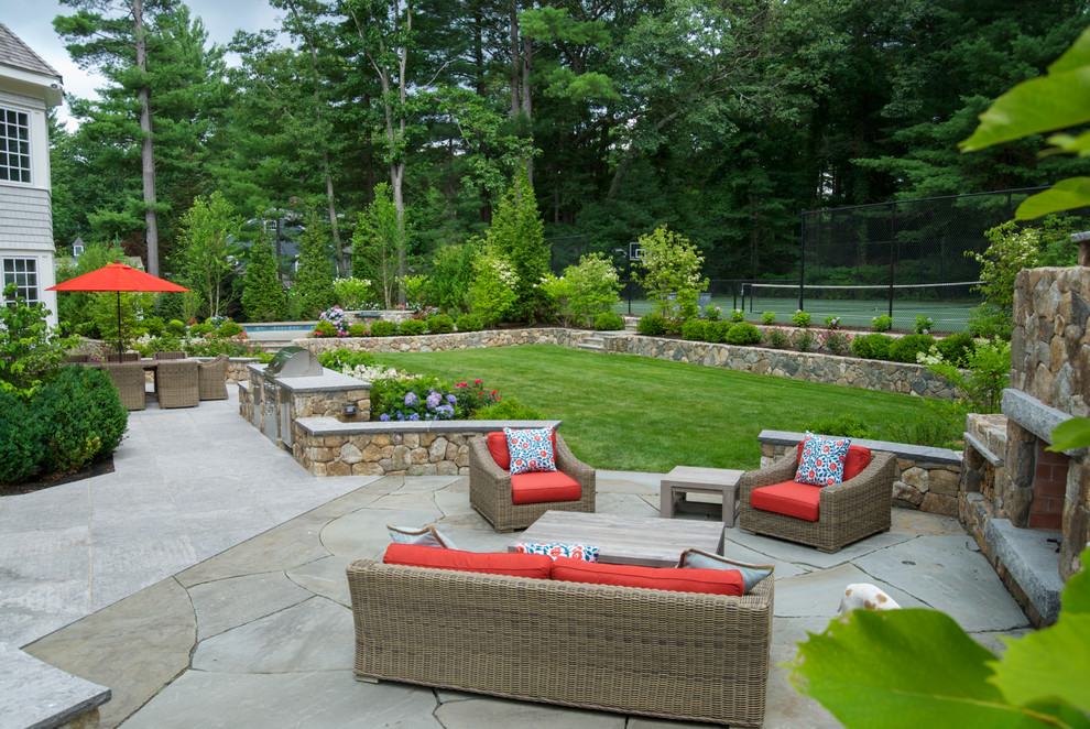 Example of a large classic backyard stone patio design in Boston