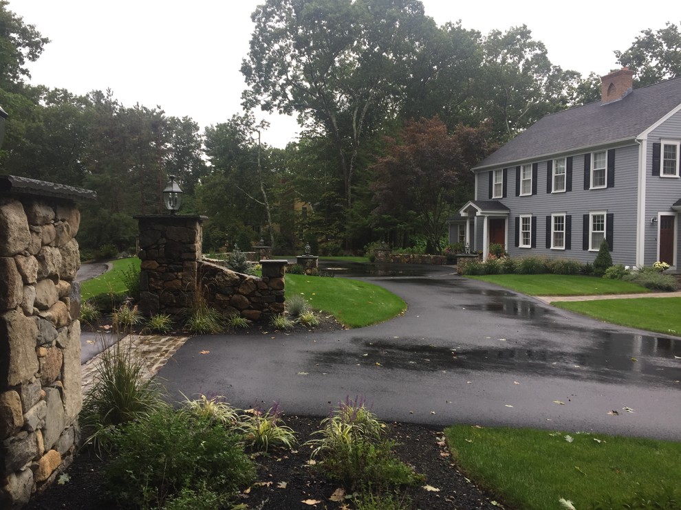 This is an example of a mid-sized traditional partial sun front yard stone driveway in Boston.
