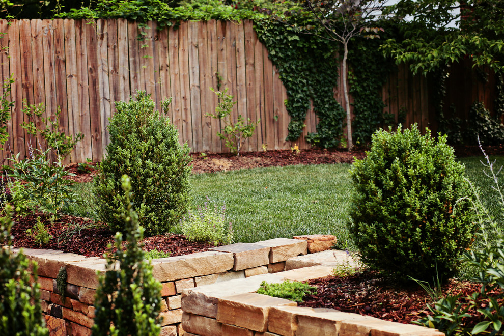 This is an example of a small traditional full sun backyard stone retaining wall landscape in Charlotte for summer.