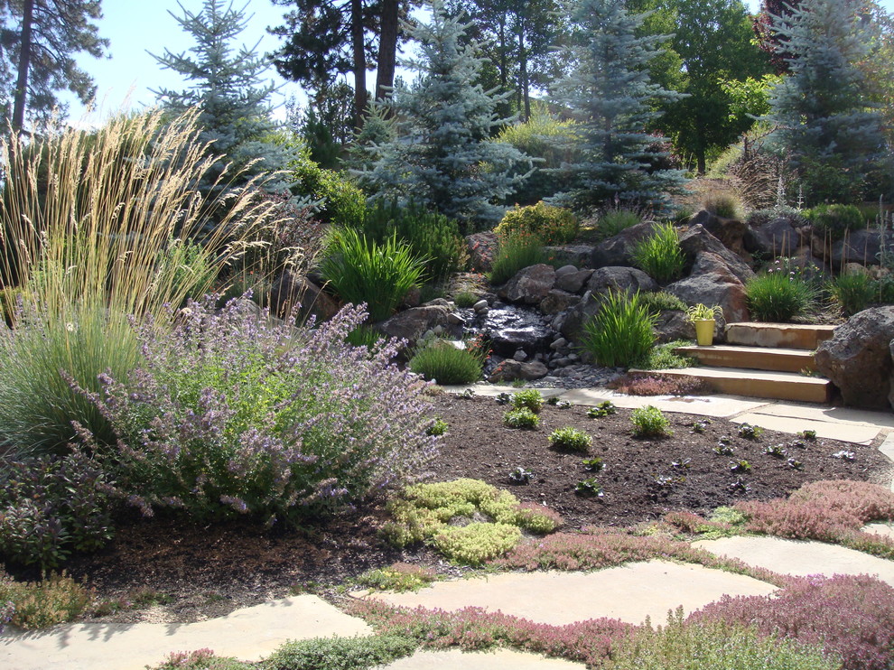 Idee per un giardino xeriscape mediterraneo esposto in pieno sole dietro casa con pavimentazioni in pietra naturale