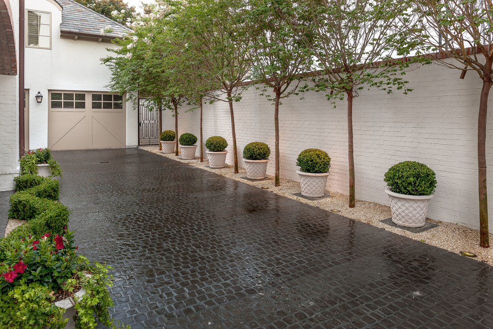 This is an example of a mid-sized traditional partial sun stone driveway in Houston.