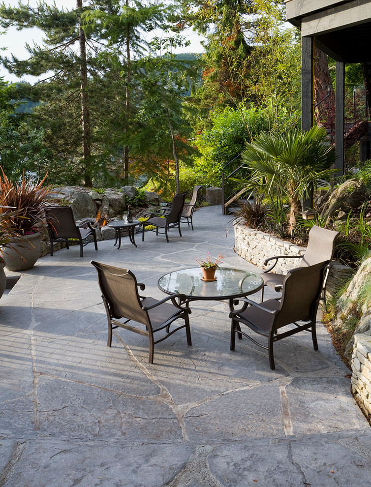 Medium sized modern patio in Vancouver with a fire feature and natural stone paving.