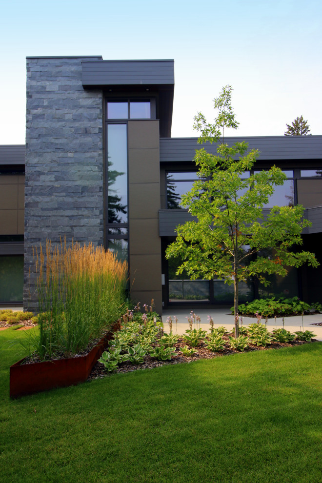 Photo of a large modern courtyard formal partial sun garden in Edmonton with mulch.