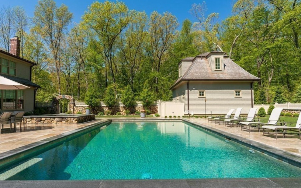 Klassisk inredning av en mycket stor pool insynsskydd och på baksidan av huset, med naturstensplattor