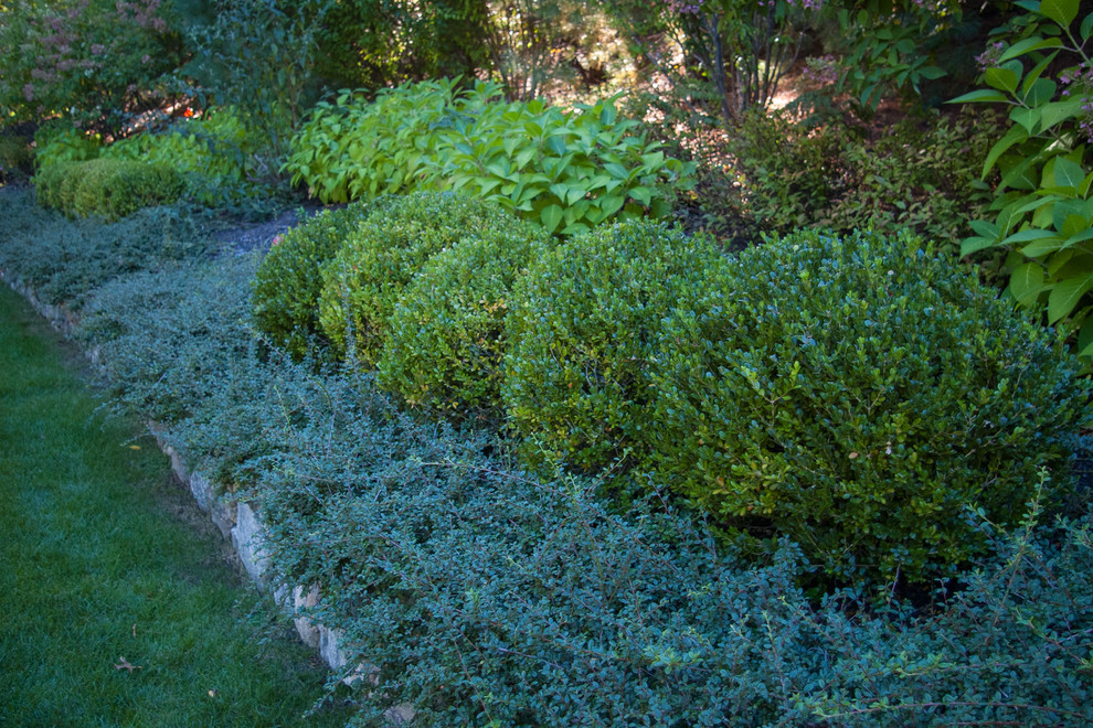 На фото: большой участок и сад на переднем дворе в классическом стиле с подпорной стенкой, полуденной тенью и покрытием из каменной брусчатки