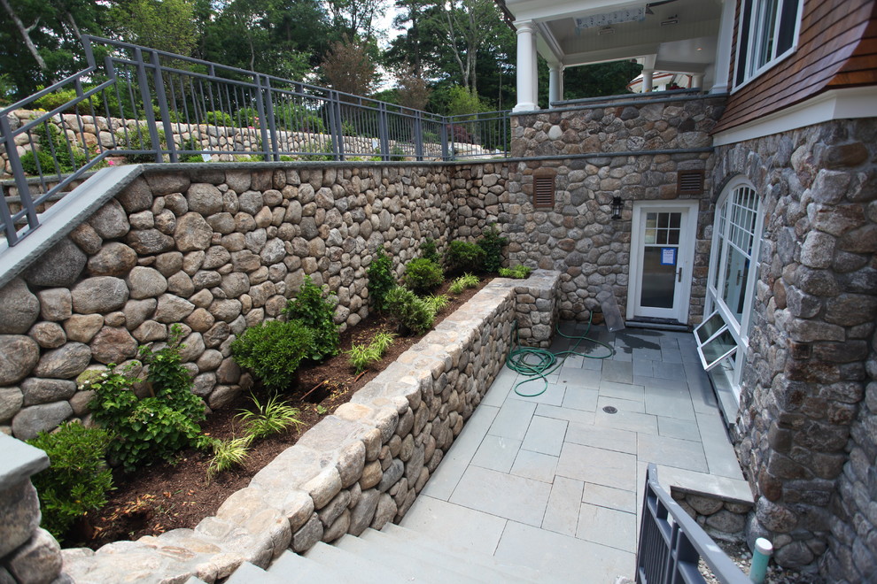 Photo of a large classic back formal full sun garden in Boston with a water feature and natural stone paving.