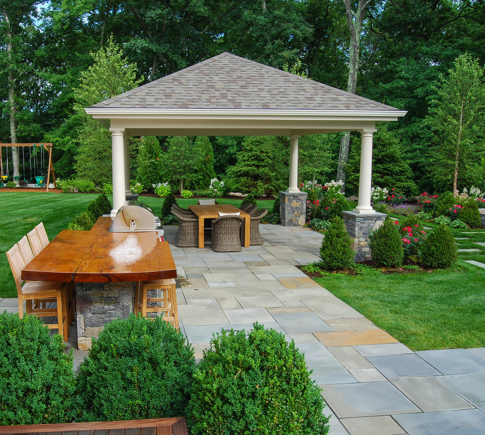Modelo de patio clásico grande en patio trasero con adoquines de piedra natural