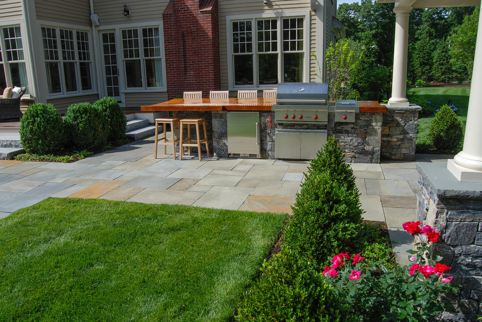 Imagen de patio clásico grande en patio trasero con adoquines de piedra natural
