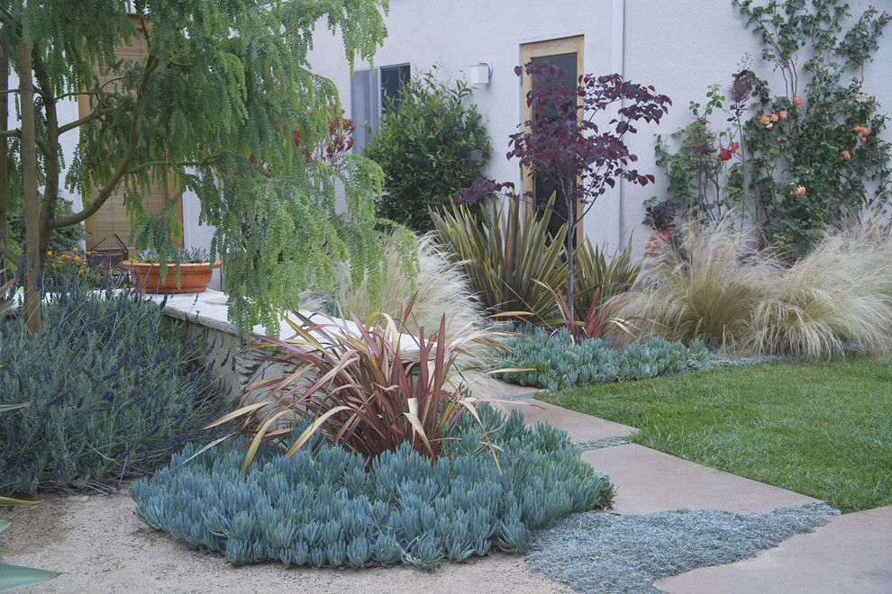 Modelo de jardín moderno de tamaño medio en patio trasero con jardín francés, exposición parcial al sol y adoquines de hormigón