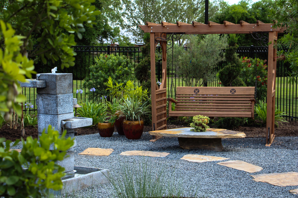 Diseño de jardín de estilo americano extra grande en patio trasero con jardín francés, fuente, exposición total al sol y gravilla