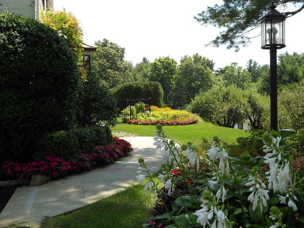 Inspiration för stora klassiska trädgårdar i delvis sol längs med huset på sommaren, med naturstensplattor