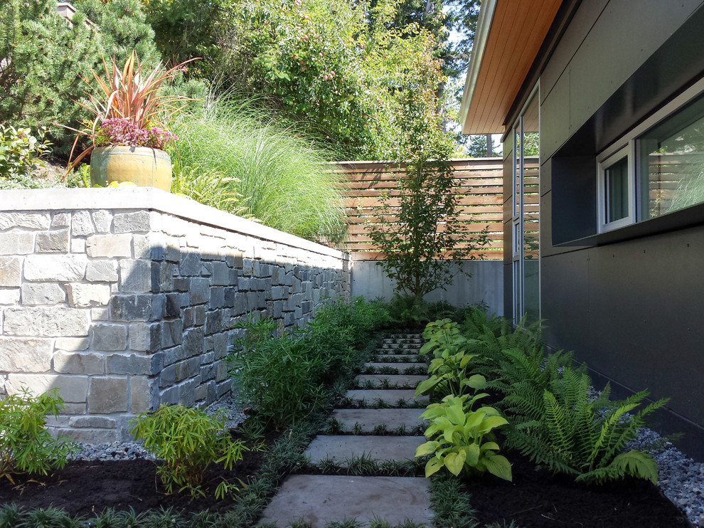 Idée de décoration pour un jardin latéral design avec une exposition partiellement ombragée et des pavés en pierre naturelle.