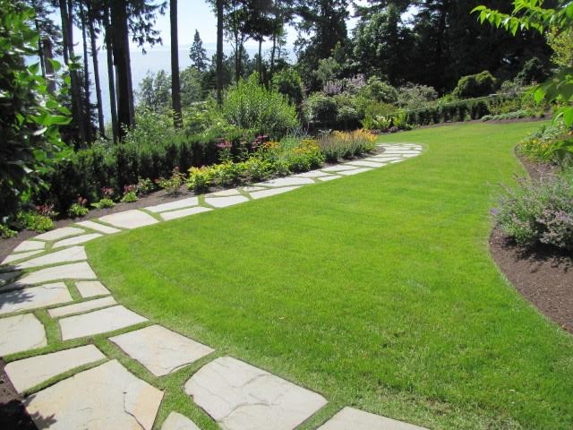 Aménagement d'un grand jardin arrière classique avec une exposition ensoleillée et des pavés en pierre naturelle.