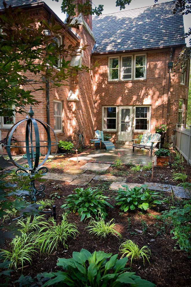 Imagen de jardín clásico de tamaño medio en patio trasero con exposición reducida al sol y adoquines de piedra natural