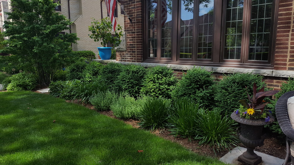 Photo of a small classic front formal full sun garden for summer in Milwaukee with brick paving.
