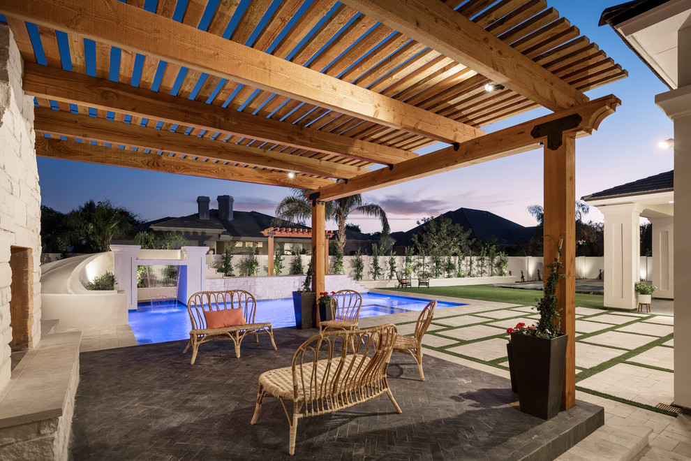 Expansive traditional back patio in Phoenix with a fire feature and natural stone paving.