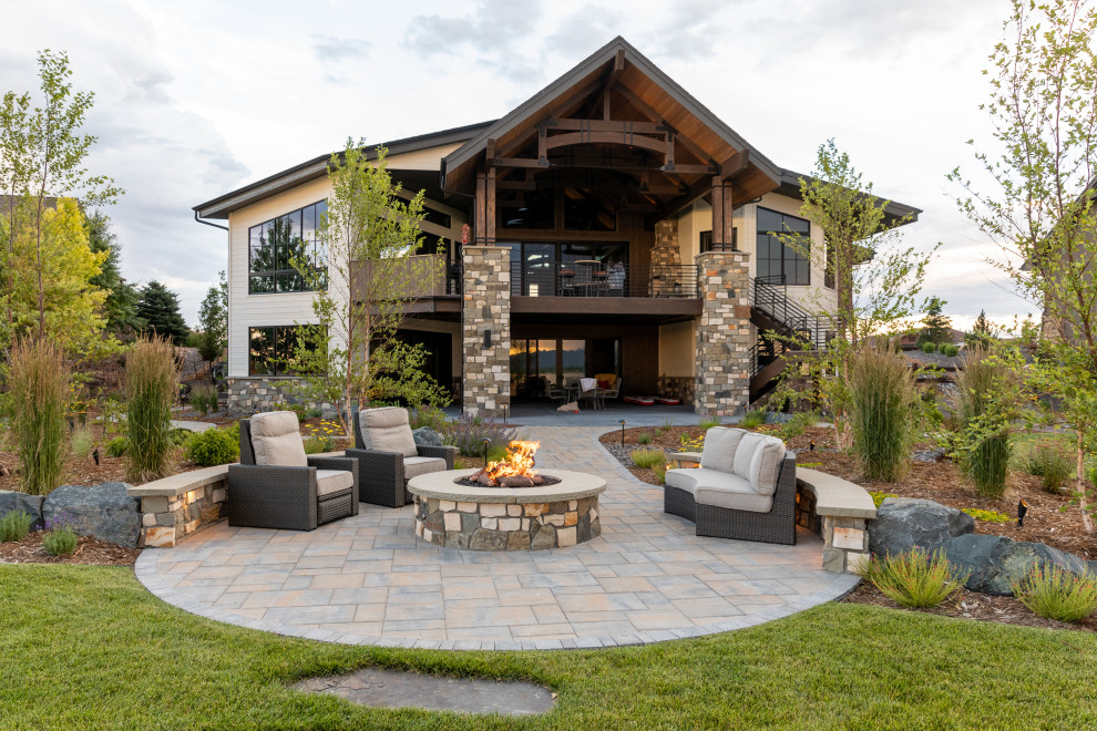 This is an example of an expansive classic back full sun garden in Denver with a fire feature and concrete paving.