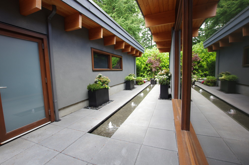 Inspiration for a modern shade courtyard concrete paver water fountain landscape in Vancouver.