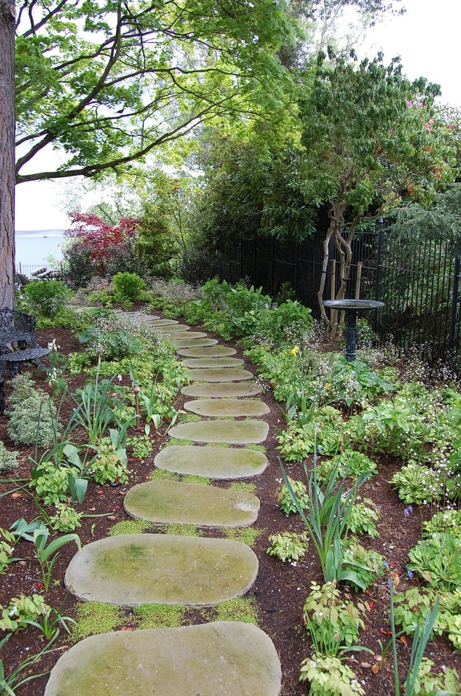 Cette image montre un très grand jardin latéral traditionnel au printemps avec une exposition ombragée et des pavés en pierre naturelle.