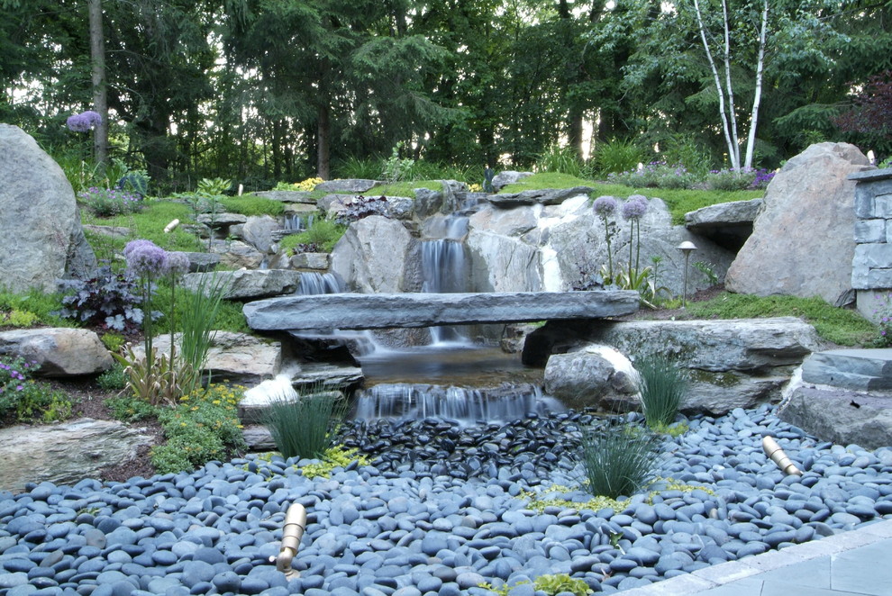 Idee per un grande laghetto da giardino chic esposto a mezz'ombra dietro casa con pavimentazioni in pietra naturale