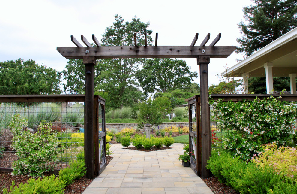 Esempio di un giardino country con cancello, pavimentazioni in cemento e recinzione in metallo