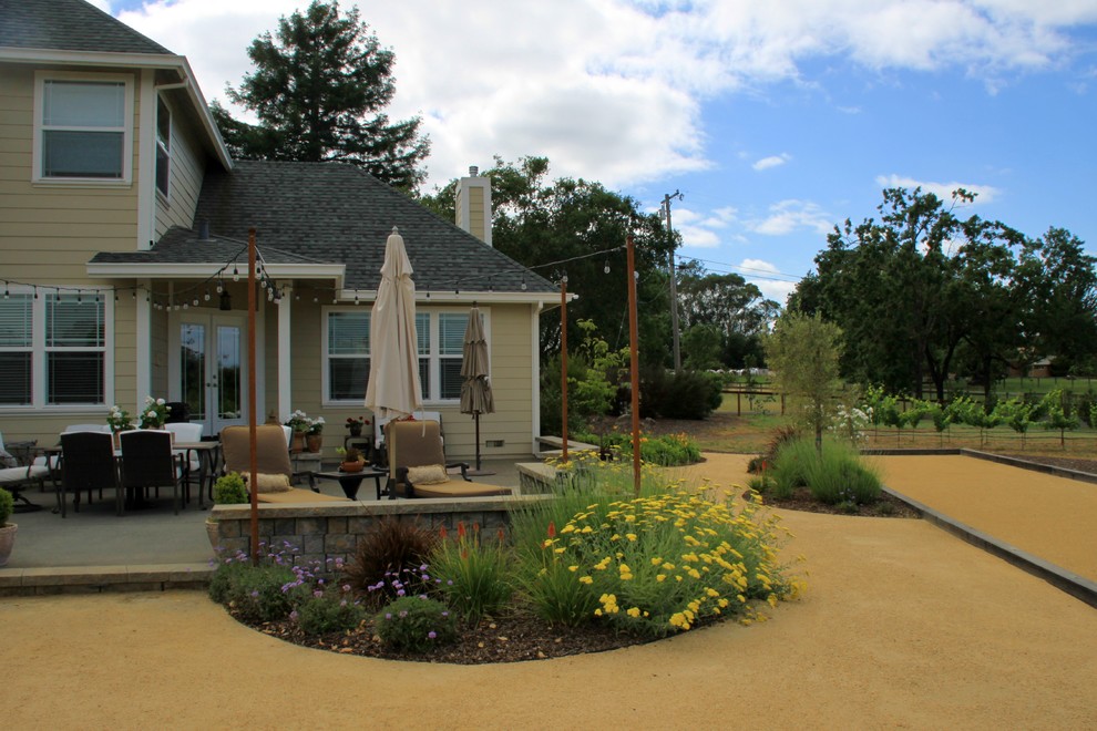 Idee per un ampio giardino formale country esposto in pieno sole dietro casa in estate con un muro di contenimento e pavimentazioni in cemento