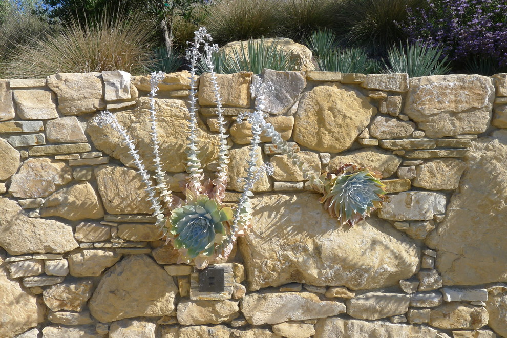 Photo of a large mediterranean partial sun backyard stone landscaping in San Luis Obispo with a fire pit.