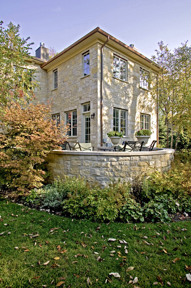 Modelo de jardín clásico en otoño en patio delantero con muro de contención y adoquines de piedra natural