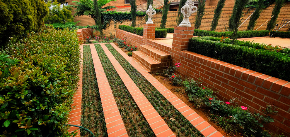 Exempel på en mycket stor medelhavsstil formell trädgård pallkragar och i slänt, med marksten i tegel