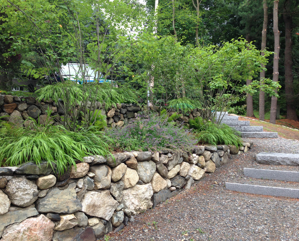 Exemple d'un grand jardin arrière chic avec un mur de soutènement, une exposition partiellement ombragée et du gravier.