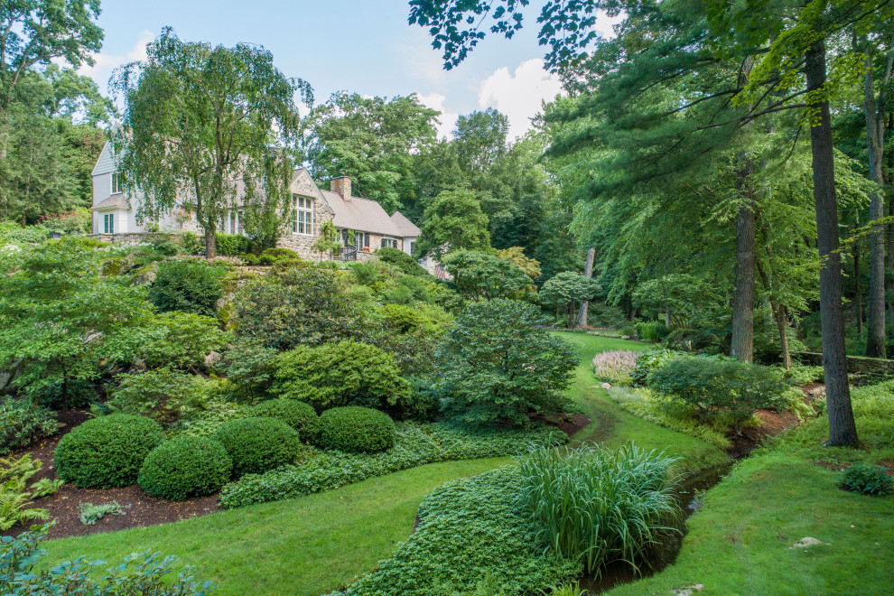 Aménagement d'un grand jardin à la française classique l'été avec un massif de fleurs, une exposition ensoleillée et une pente, une colline ou un talus.