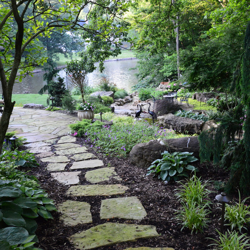 Idee per un grande laghetto da giardino chic dietro casa con pavimentazioni in pietra naturale