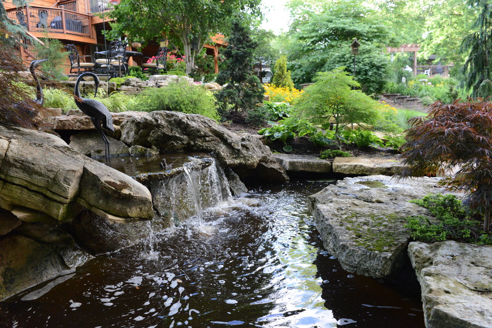 Inspiration pour un grand jardin arrière traditionnel avec un point d'eau et des pavés en pierre naturelle.