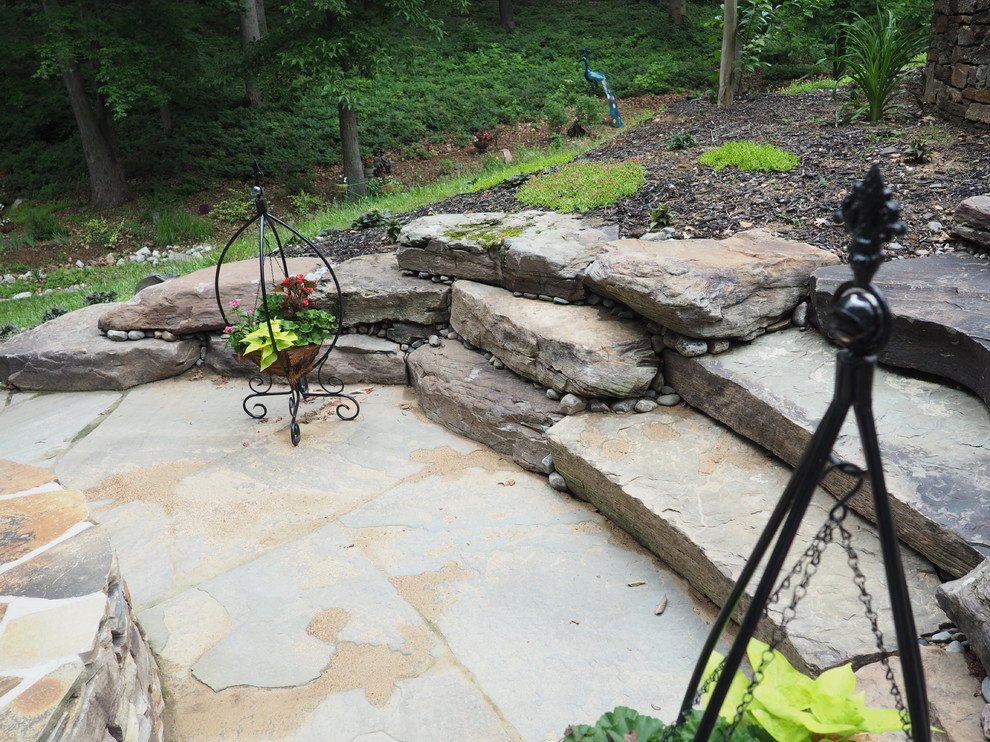 Пример оригинального дизайна: большой летний засухоустойчивый сад на склоне в стиле рустика с подпорной стенкой, полуденной тенью и покрытием из каменной брусчатки