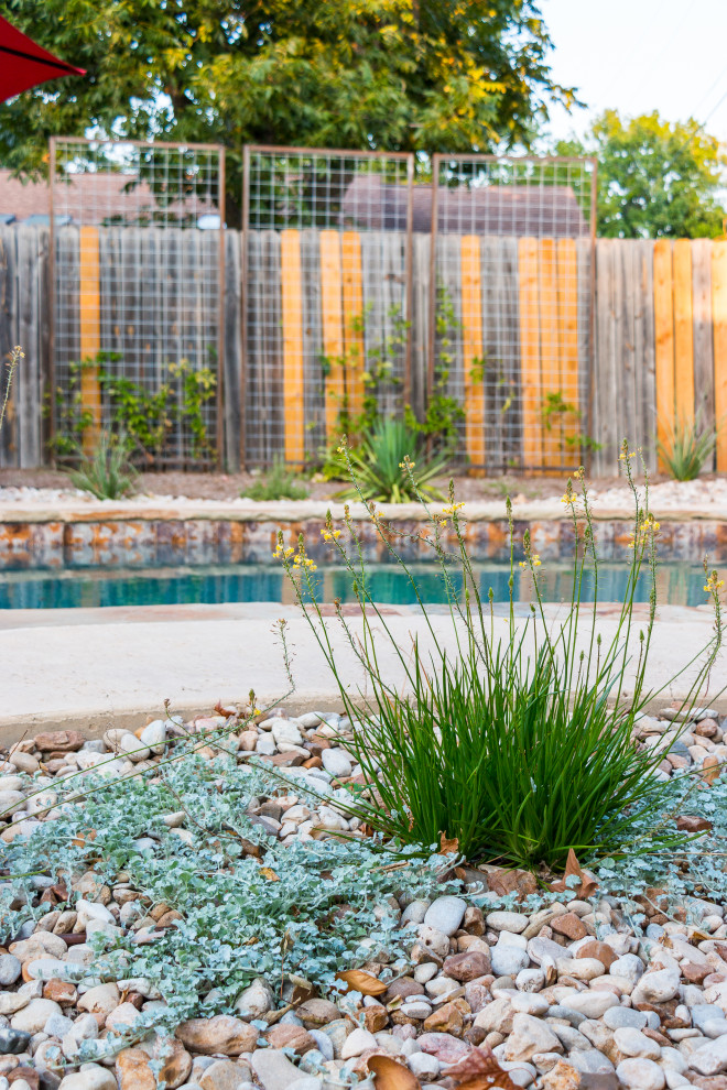 Design ideas for a mid-sized contemporary drought-tolerant, desert and partial sun backyard wood fence and river rock landscaping in Austin for summer.