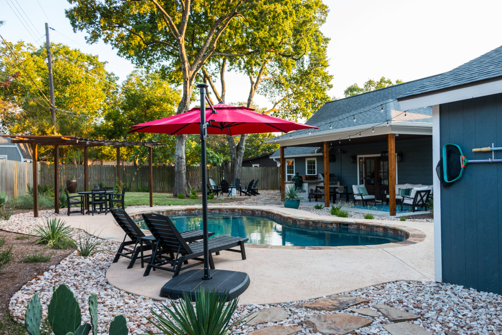 Inspiration for a mid-sized contemporary drought-tolerant, desert and partial sun backyard wood fence and river rock landscaping in Austin for summer.