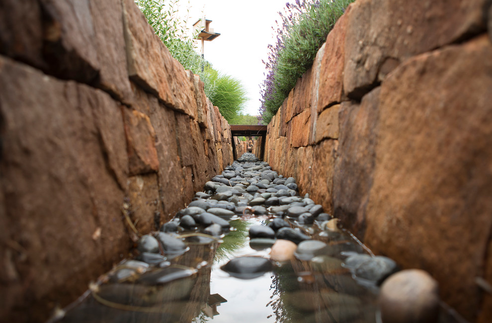 Contemporary back xeriscape full sun garden for summer in Albuquerque with a water feature and natural stone paving.