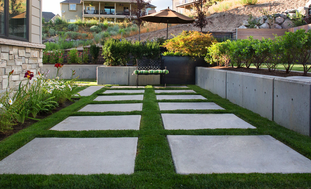 Esempio di un giardino minimal di medie dimensioni e nel cortile laterale con un muro di contenimento e pavimentazioni in cemento