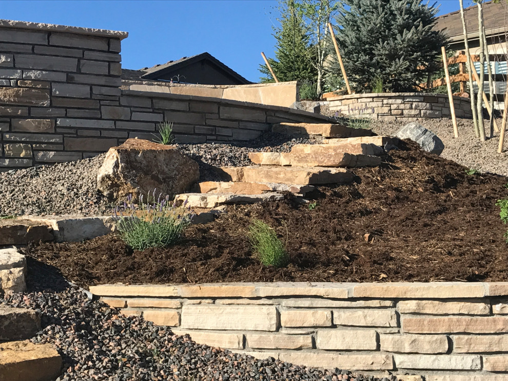 This is an example of a medium sized contemporary front xeriscape full sun garden in Denver with a retaining wall.