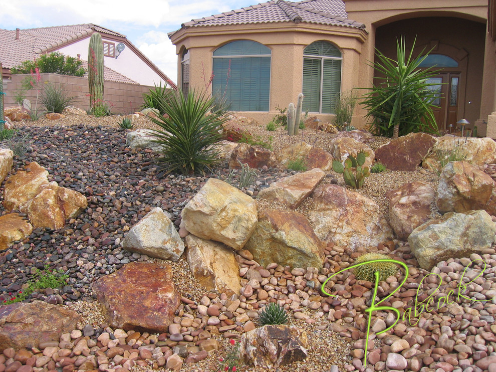 Photo of a small front xeriscape full sun garden for summer in Other with a desert look, brick paving and a stone fence.