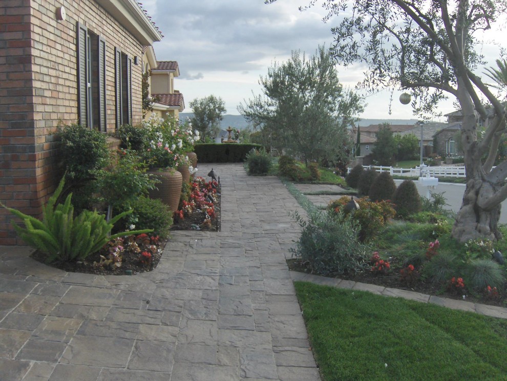 Large classic front driveway full sun garden in Orange County with natural stone paving.