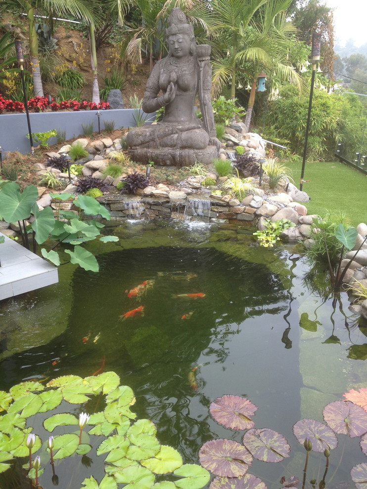 This is an example of an asian full sun backyard stone water fountain landscape in Los Angeles.