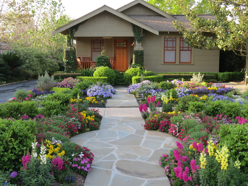 Bild på en mellanstor amerikansk trädgård framför huset och blomsterrabatt på sommaren, med naturstensplattor