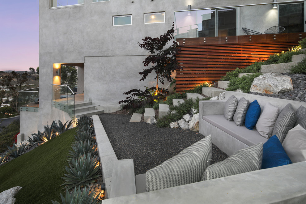 Contemporary sloped full sun garden in Orange County with a retaining wall and gravel.