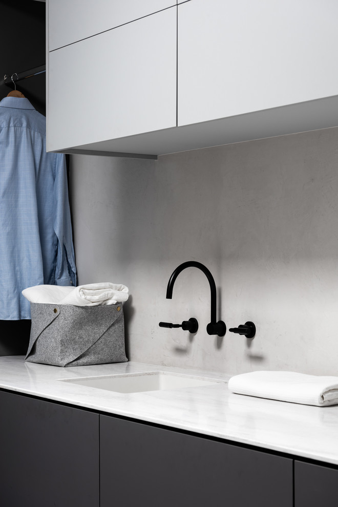 Exempel på en mellanstor industriell vita linjär vitt tvättstuga enbart för tvätt, med en undermonterad diskho, släta luckor, grå skåp, bänkskiva i koppar, grå väggar, betonggolv och grått golv